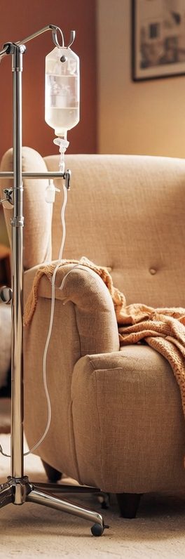 Infusionsständer neben einem beigen Sofa mit einer Decke.
