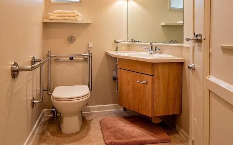 Barrierefreies Bad mit Waschbecken, Toilette und Haltegriffen.